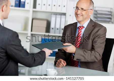 Businessman giving his job application to the employer inside the office