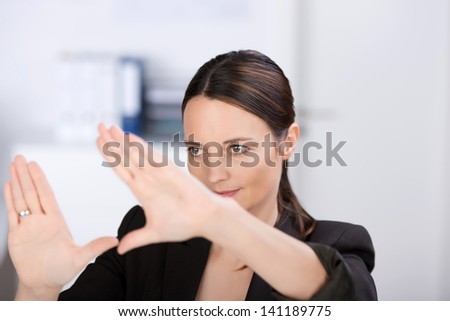 Mid adult businesswoman making hand frame in office, focus eyes
