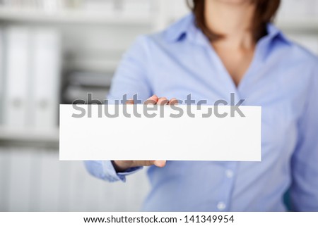Midsection of woman holding blank paper in office