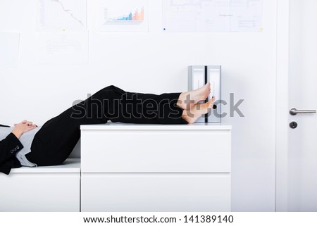 Side view of businesswoman legs sleeping on counter in office