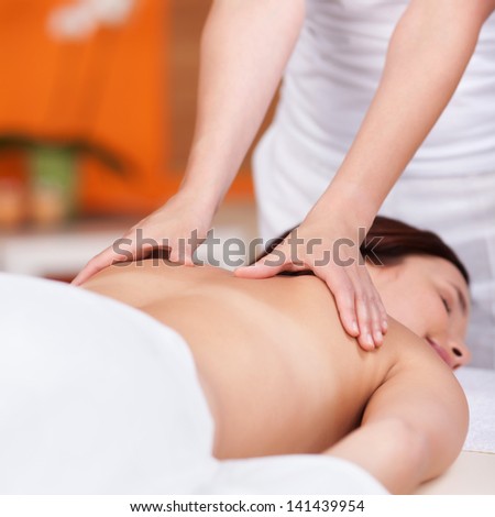Masseuse is working the back of a young woman