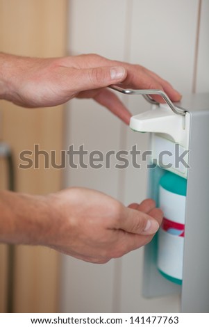 Doctors hands using sanitizer dispenser in washroom