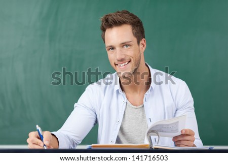 Portrait of a happy student in front of a green chalkboard