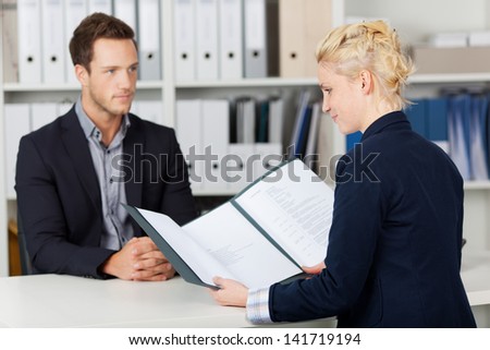 a recruiter looking at resume in front of an applicant