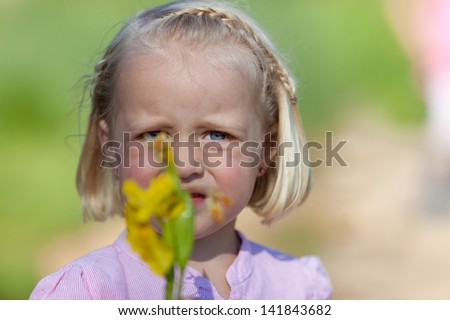 Portrait of little girl crying with yellow flower over the blurred background