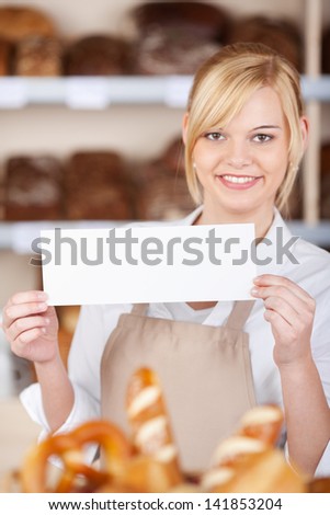 smiling saleswoman in bakery displaying blank paper