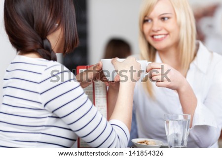 Young businesswoman with coworker holding coffee cup in office cafe