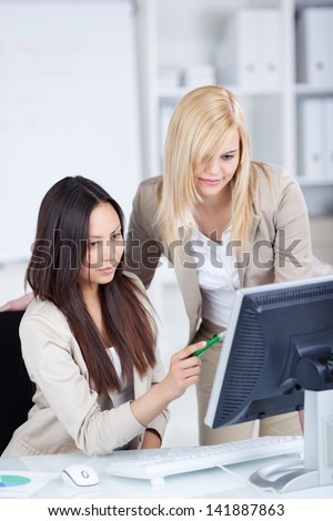 two young female co worker working together on computer