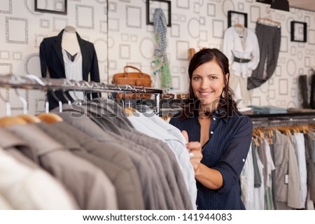 Portrait of happy female customer choosing shirt in clothing store