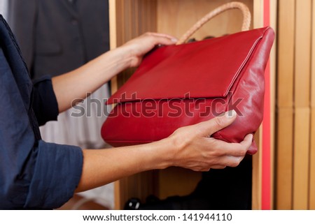 closeup of woman hands holding red handbag in store