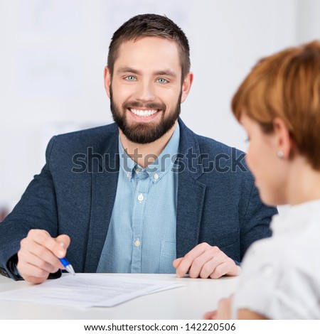 Young businessman explaining documents to female co worker at office desk