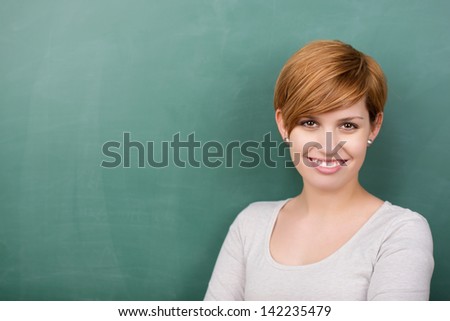 Portrait of confident female professor smiling against chalkboard