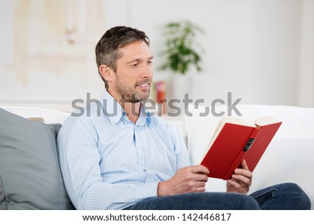 Handsome mature man reading red book in house