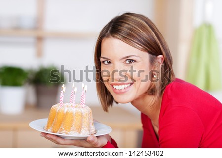 Beautiful smiling woman holding a small birthday cake with burning candles