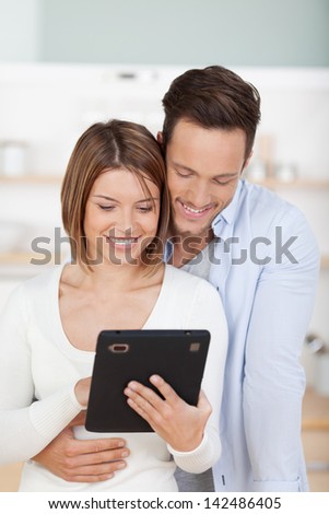Sweet cuddling couple searching something through digital tablet
