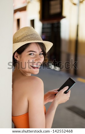 Beautiful happy woman wearing hat texting through cellphone