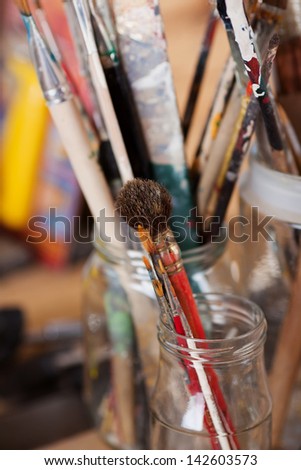 Closeup of paint brushes in glass jar at workshop
