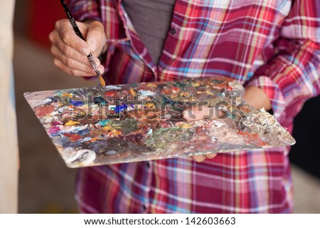 Closeup of woman mixing paint on palette at workshop