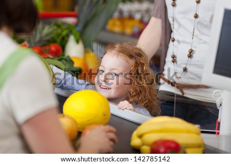 Image of a cute girl at the checkout counter in the supermarket.