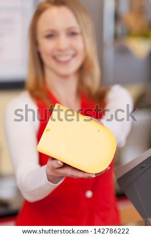 Portrait of saleswoman displaying cheese in grocery store