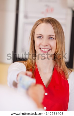 Happy saleswoman receiving money from customer in grocery store