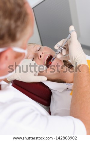 Dentist giving injection to a female patient in the clinic