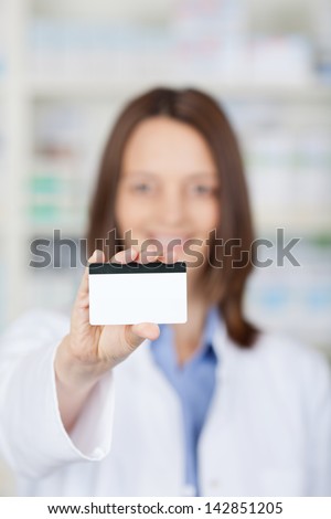 Closeup of a female pharmacist showing a membership card inside the drugstore.