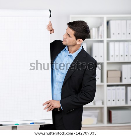 Well dressed businessman wearing a nice black suit looking at flipchart in the office.