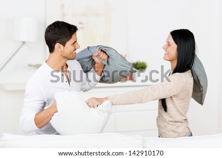 Happy young couple having pillow fight in house