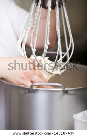 Bakery worker holding a beater in a food mixer