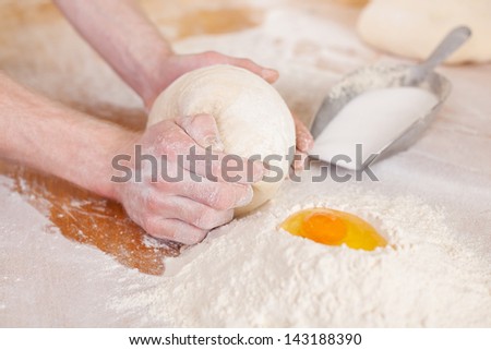 Baker kneading fresh dough in a bakery while preparing a specialist gourmet loaf