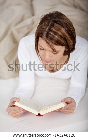 Closeup photo of a woman reading a book in bed, reading and relaxing before going to sleep.