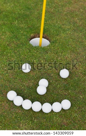 High angle view of smiley face made of golf balls on grassy field