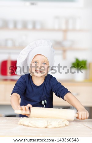 Portrait of cute little girl using rolling pin on dough at kitchen counter
