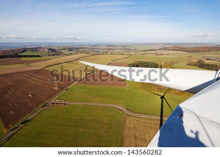 View from the wind of wind turbine over the green fields