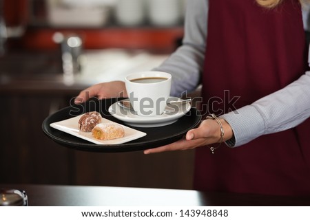 close-up of a waitress serving a cup of coffee and snacks