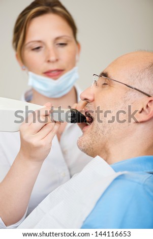 Female dentist with dental camera examining teeth at clinic