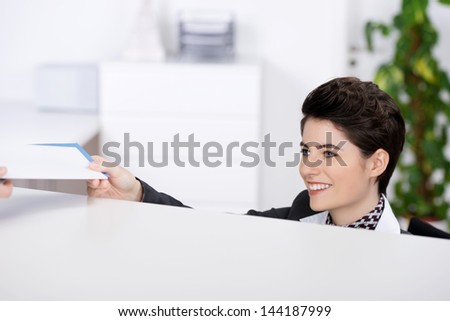 Happy young receptionist giving traveling documents at reception counter