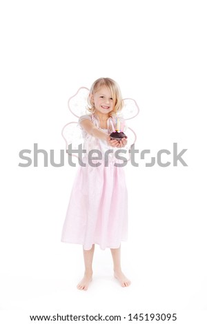 Small little blond girl dressed as a fairy with a birthday cake and candles held in her outstretched hands, isolated on white