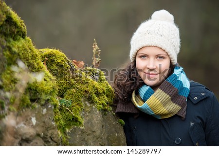 Smiling woman outdoors in winter dressed up warmly in a knitted scarf and cap