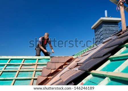 Close view of beams with a man working on the roof in the background