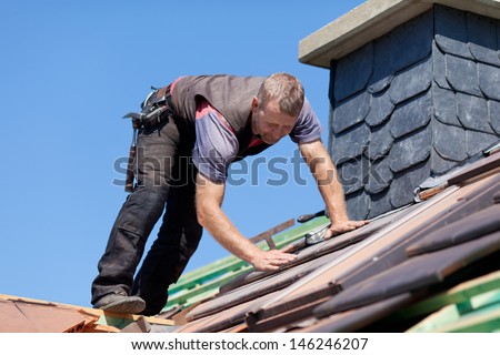 Roofer next to the chimney verifying the tiles