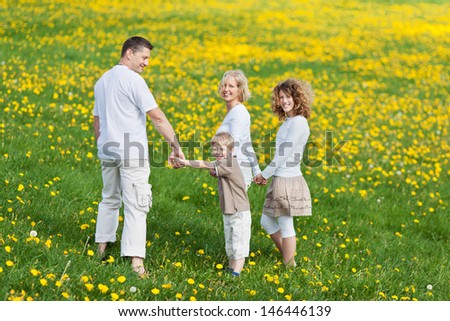 family walking on grassy field looking back