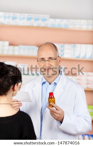 Smiling male pharmacist giving prescription to the customer at workplace