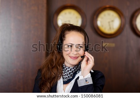 Friendly receptionist wearing a headset listening to a call while giving a beautiful smile