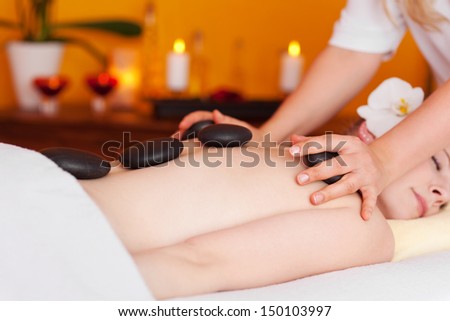 Woman laying face-down while receiving a massage with hot stones in a stylish beauty center