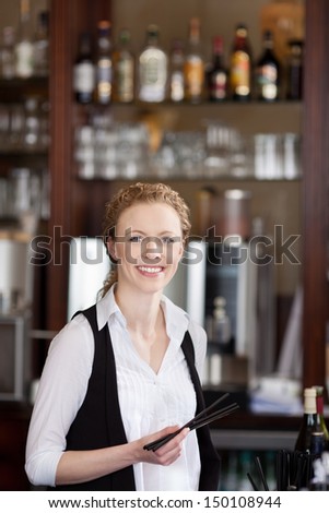 Attractive young waitress holding straws with blurres bottles of liquor in the background
