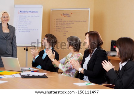 Business class applauding the female lecturer at the end of a training class or presentation