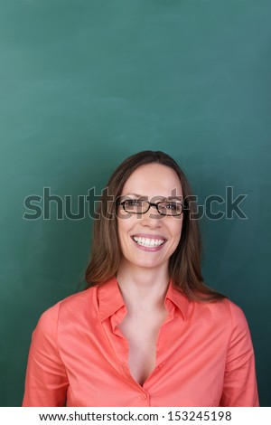 Beautiful woman with a lovely beaming smile wearing glasses standing against a green background with copyspace