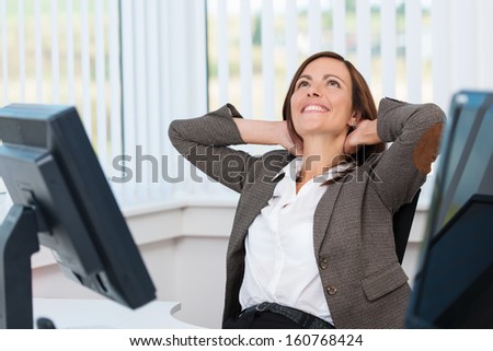 Happy businesswoman sitting at her desk and leaning back while stretching